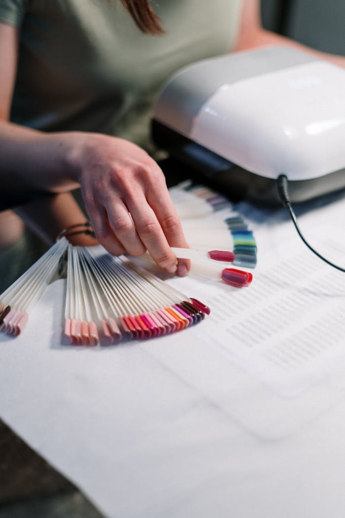 Close-up of a manicurist selecting nail polish colors in a salon setting.